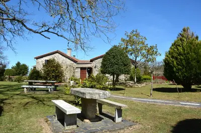 a stone bench in front of a house at Duerming Casa Vilamor in Vilamor
