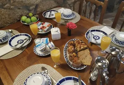 a wooden table with plates of food and glasses of orange juice at Duerming Casa Vilamor in Vilamor