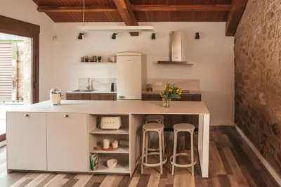 a kitchen with white cabinets and a counter with stools at ACASADETEO in Padrón