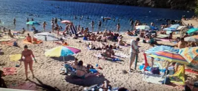 a crowd of people on a beach with umbrellas at Casa Mariana in Lubián