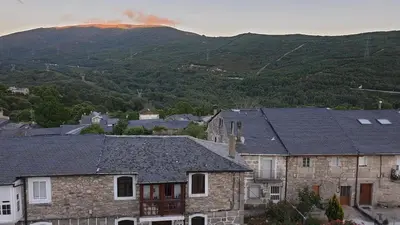 a group of houses with a mountain in the background at Casa Mariana in Lubián