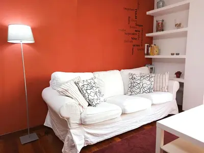a white couch in a living room with an orange wall at Viveiro Histórico 3 in Viveiro