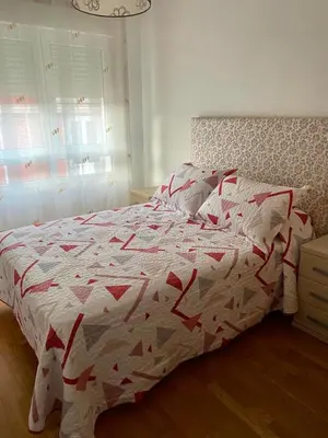 a bedroom with a bed with a red and white comforter at Piso Vista os castelos in Viveiro