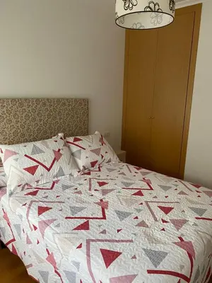 a bed with a red and white quilt on it at Piso Vista os castelos in Viveiro