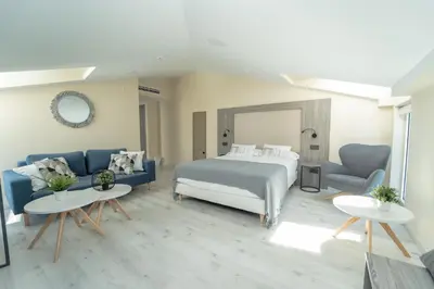 a bedroom with a bed and a couch and tables at Hotel Lux Melide in Melide