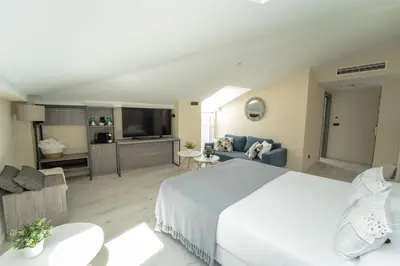a bedroom with a large bed and a living room at Hotel Lux Melide in Melide