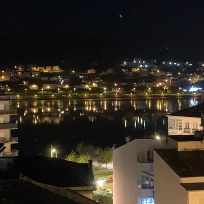 a night view of a city and a body of water at Apartamento Porta da Vila in Viveiro