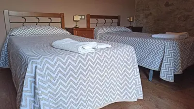 two beds in a hotel room with towels on them at Hotel Rural Val Dos Pigarros in Lubián