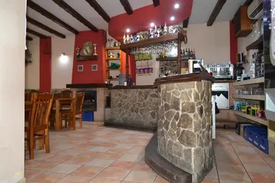 a bar in a restaurant with red walls at Hotel Rural Val Dos Pigarros in Lubián