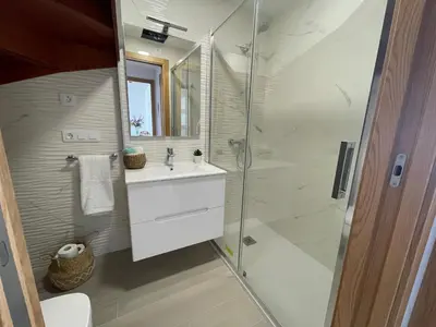 a bathroom with a glass shower and a sink at Viviendas Vacacionales ENTREPLAYAS. Foz. in Foz
