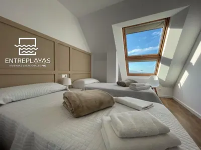 two twin beds in a room with a window at Viviendas Vacacionales ENTREPLAYAS. Foz. in Foz