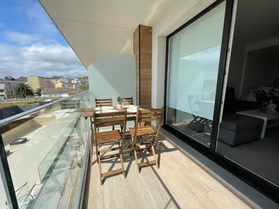 a balcony with a wooden table and chairs on it at Viviendas Vacacionales ENTREPLAYAS. Foz. in Foz