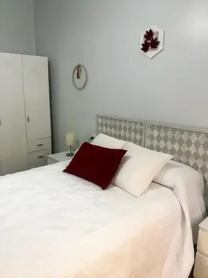 a white bed with a red pillow on top of it at El 0tro Cuartín in Ponferrada