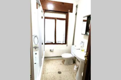 a bathroom with a toilet and a sink and a window at Covas Beach Garden in Viveiro