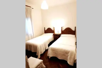 two beds in a room with white sheets at Covas Beach Garden in Viveiro
