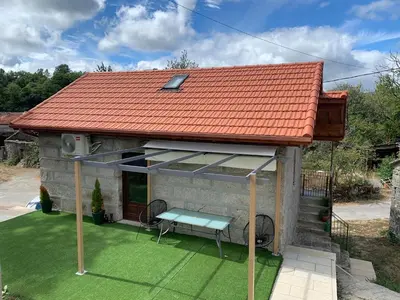 a small house with an orange roof and a bench at CASA TIO HERMINIO in O Irixo