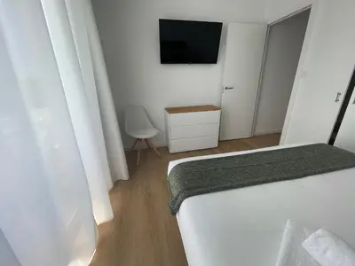 a white bedroom with a bed and a tv at Oktheway Perbes Beach 2 in Boebre