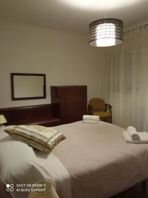 a bedroom with a large bed and a chandelier at Casa do Pombar en Valdeorras in Seadur