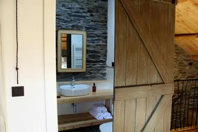 a bathroom with a sink and a mirror and a door at Casa Rural Estrella del Sil in Corbón del Sil