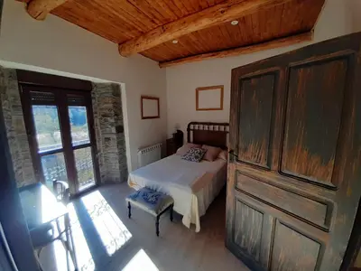a bedroom with a bed and a large wooden door at Casa Rural Estrella del Sil in Corbón del Sil