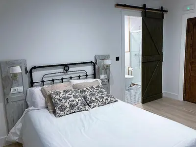 a bedroom with a white bed and a bathroom at Casa Rural Estrella del Sil in Corbón del Sil