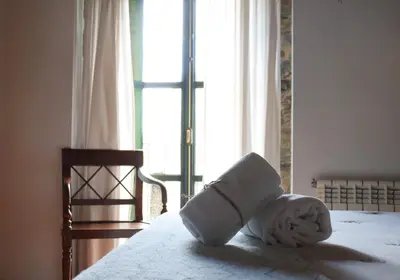a bed with a towel on it with a window at Fogar de Lecer in Arzúa