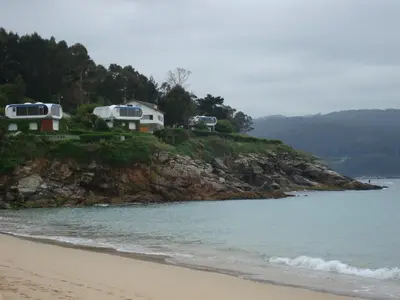 a group of rvs on a hill next to the beach at AREA PLAYA VIVEIRO APARTAMENTS , XOVE in Jove