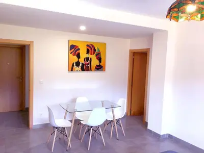 a dining room with a glass table and white chairs at AREA PLAYA VIVEIRO APARTAMENTS , XOVE in Jove