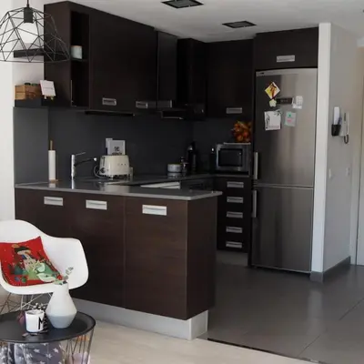 a kitchen with a stainless steel refrigerator and a chair at AREA PLAYA VIVEIRO APARTAMENTS , XOVE in Jove