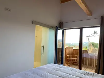 a bedroom with a bed and a balcony with a swing at Rectoral de Boente in Arzúa