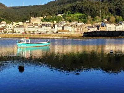 a boat sitting in the water in front of a town at Indiano 4B in Viveiro