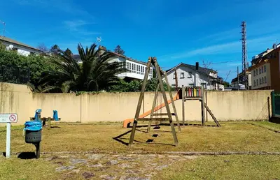 a swing set in a yard next to a fence at Indiano 4B in Viveiro