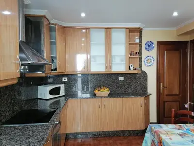 a kitchen with wooden cabinets and a bowl of fruit on the counter at Piso en pleno centro de Miño derecha in Miño
