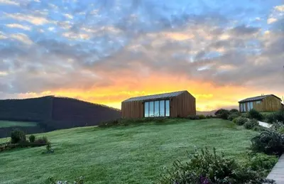 a house on a hill with a sunset in the background at Cabañas Huma 1 in Villameitide