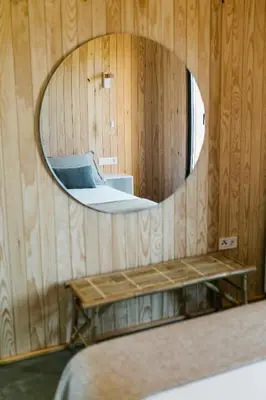 a mirror in a wooden room with a bed at Cabañas Huma 1 in Villameitide
