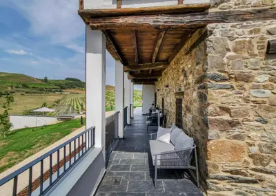 a balcony with chairs and a stone wall at Boutique Finca esencial Hotel Rural in Villafranca del Bierzo