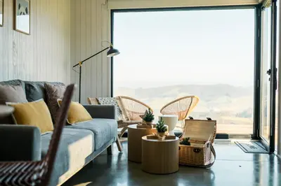 a living room with a couch and chairs and a large window at Cabañas Huma 2 in Vegadeo