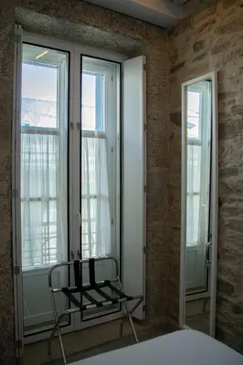 a bedroom with a chair in front of two windows at Hotel Alda San Bieito in Santiago de Compostela