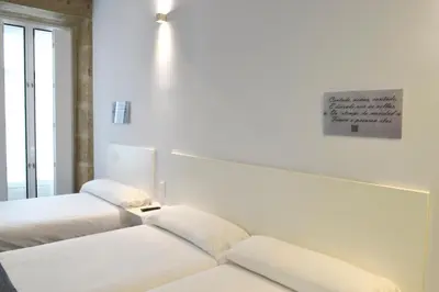 a bedroom with two beds and a sign on the wall at Hotel Alda San Bieito in Santiago de Compostela
