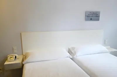 a bedroom with a white bed with a clock on it at Hotel Alda San Bieito in Santiago de Compostela