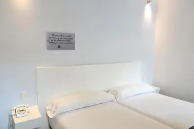 a white room with two beds and a sign on the wall at Hotel Alda San Bieito in Santiago de Compostela