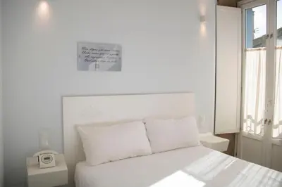 a bedroom with a white bed with a clock on it at Hotel Alda San Bieito in Santiago de Compostela