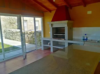 a kitchen with a stone fireplace in a room at Casa Ravel in Silleda