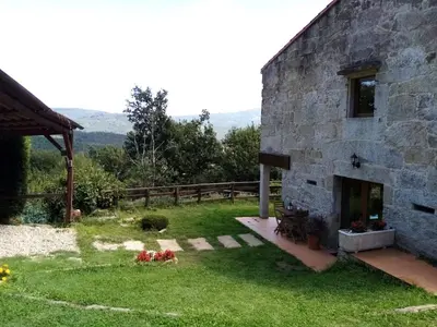 a stone house with a patio and a yard at Quinta da Rocha in Crecíente