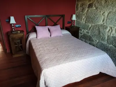 a bedroom with a large bed in a stone wall at Quinta da Rocha in Crecíente