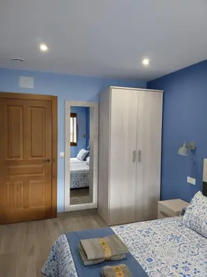 a bedroom with a bed and a cabinet with a mirror at El Rato Apartamentos Rurales in Navia