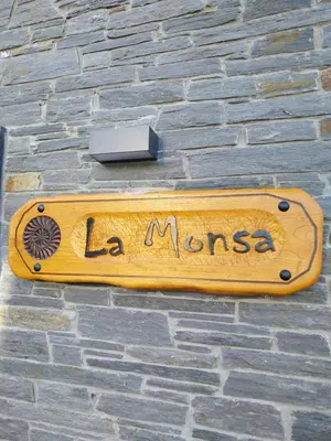 a wooden sign on the side of a brick building at El Rato Apartamentos Rurales in Navia