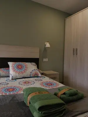 a bedroom with a bed with green towels on it at El Rato Apartamentos Rurales in Navia