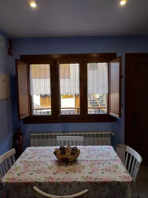 a dining room with a table and two windows at El Rato Apartamentos Rurales in Navia