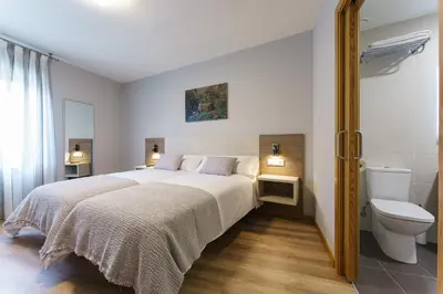 a bedroom with a white bed and a toilet at PENSIÓN CASA ELENA *** in Arzúa